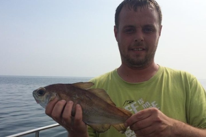 man in green shirt holding fish