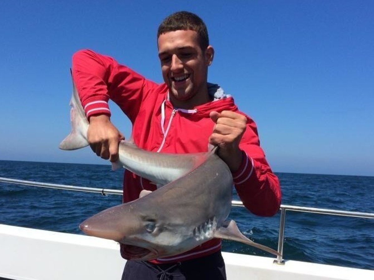 man in red hoodie holding shark