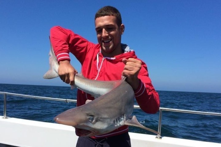 man in red hoodie holding shark