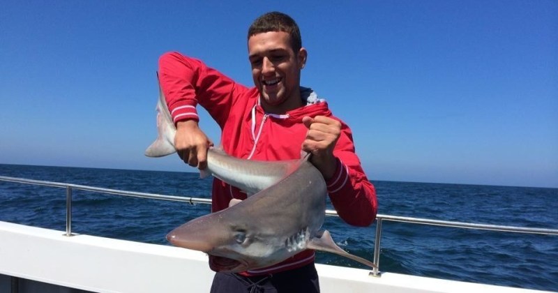man in red hoodie holding shark