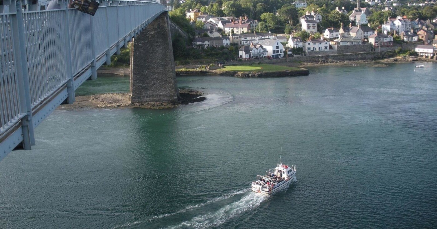 Tourists on a boat trip on the Menai Strait near Bangor, enjoying views of the coastline and historical landmarks from the water.