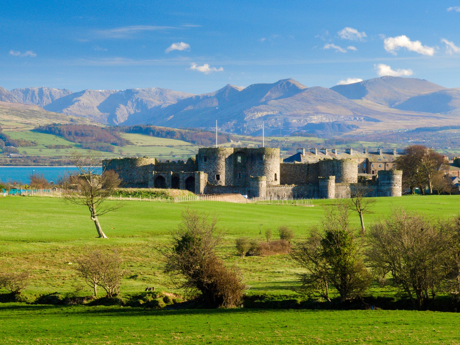a large green field with Beaumaris Castle in the background